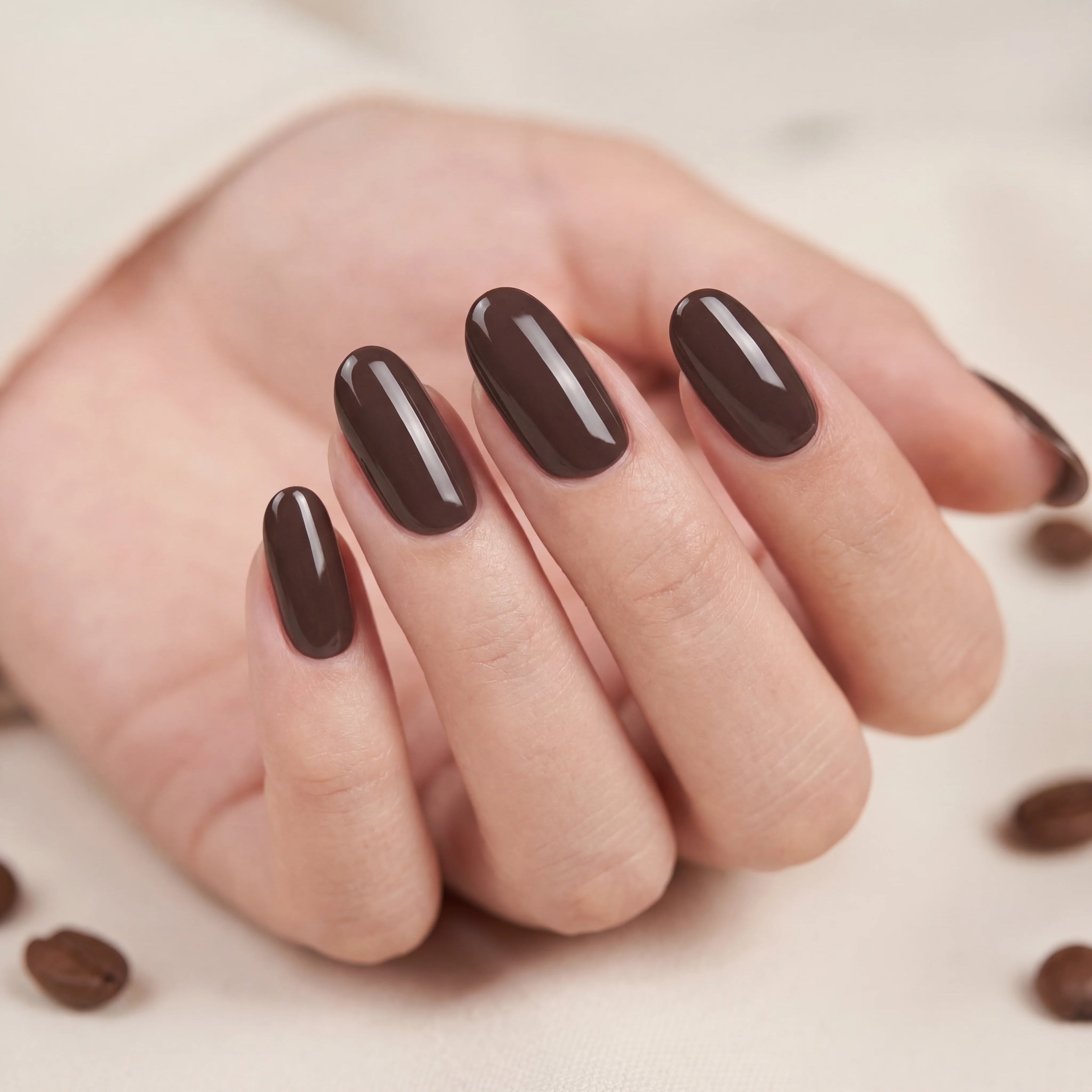 Hand with brown nail polish on a neutral background