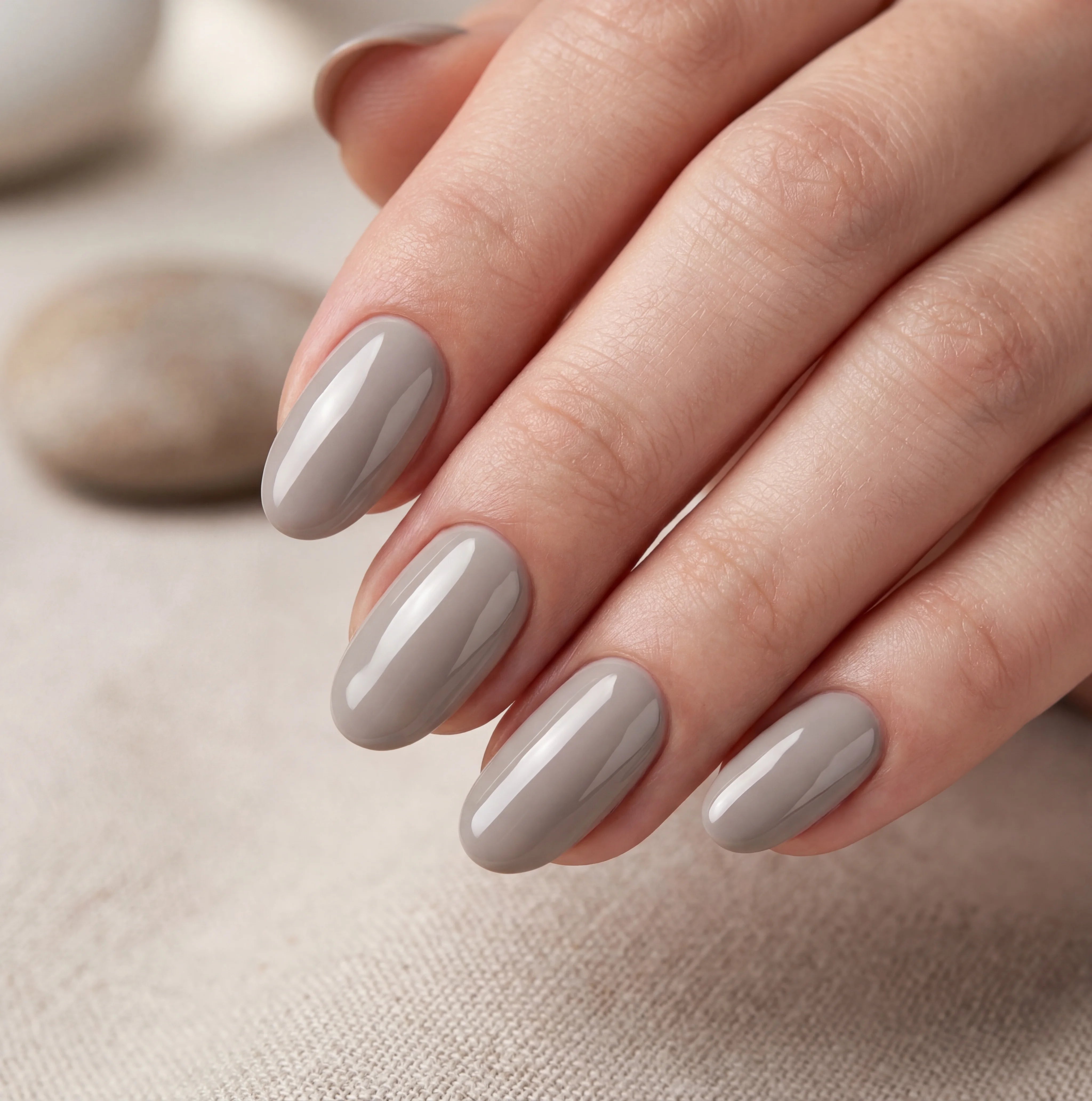 Close-up of a hand with gray nail polish on a neutral background