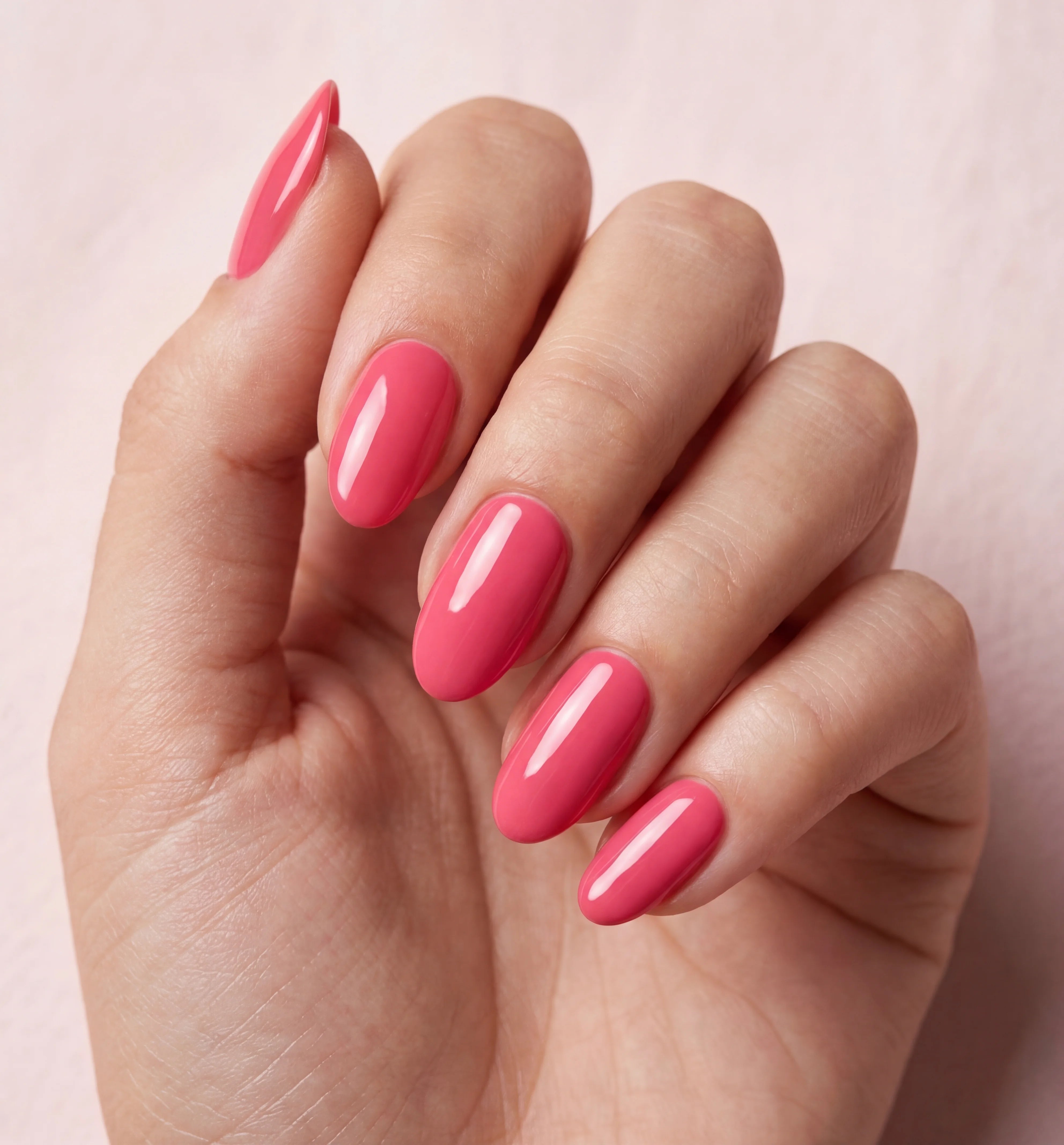 Hand with pink nail polish on a light pink background