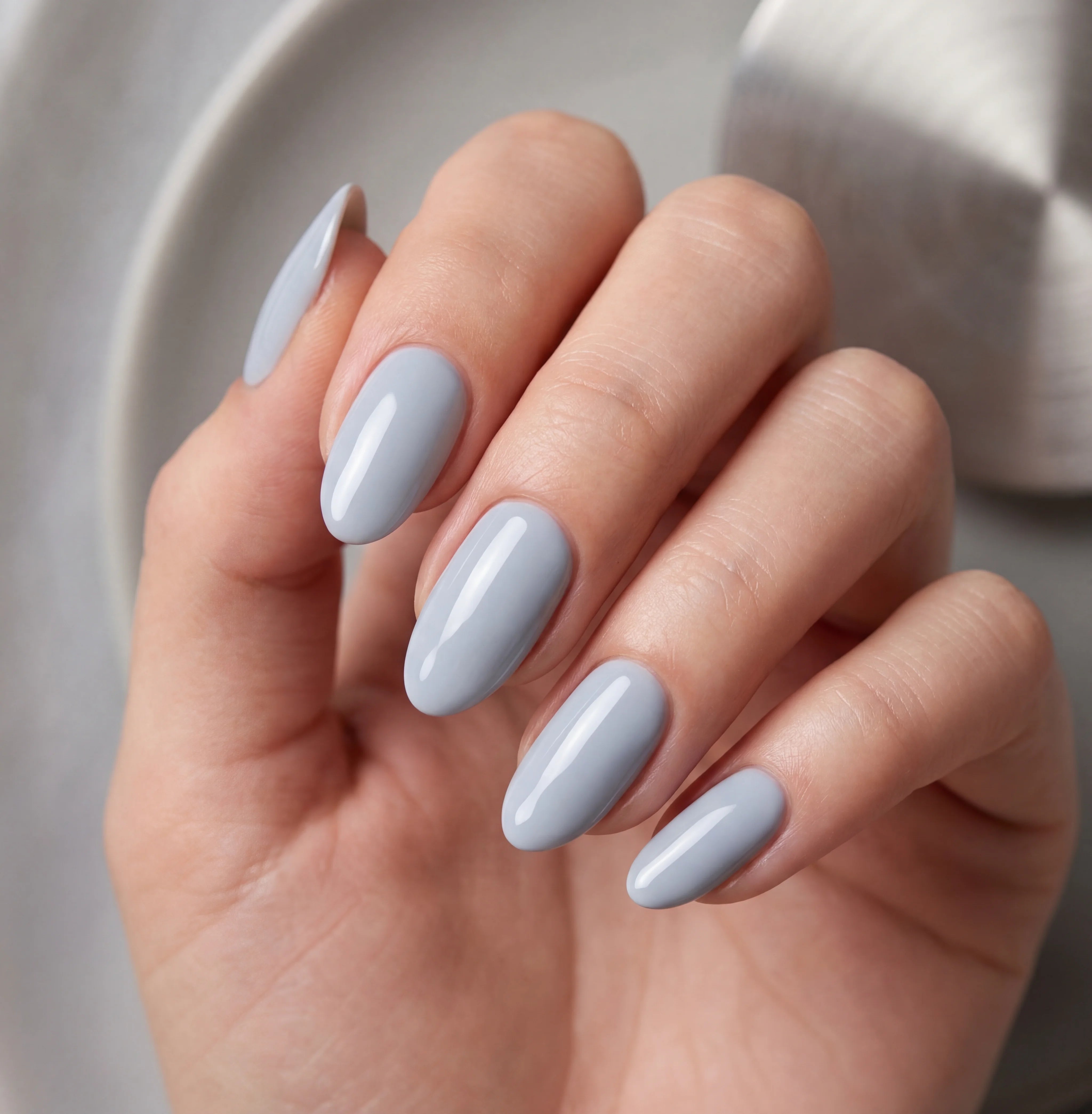 Hand with light blue nail polish on a neutral background